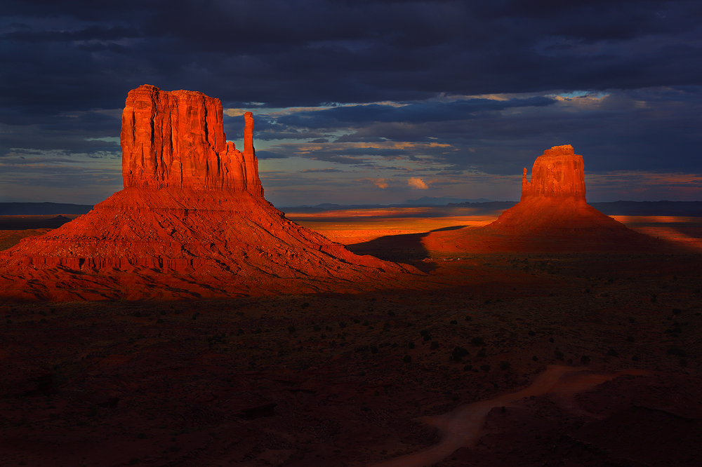 Dark storm clouds moving quickly over monument valley retreat just enough to allow a sliver of warm sunset light to briefly illuminate...