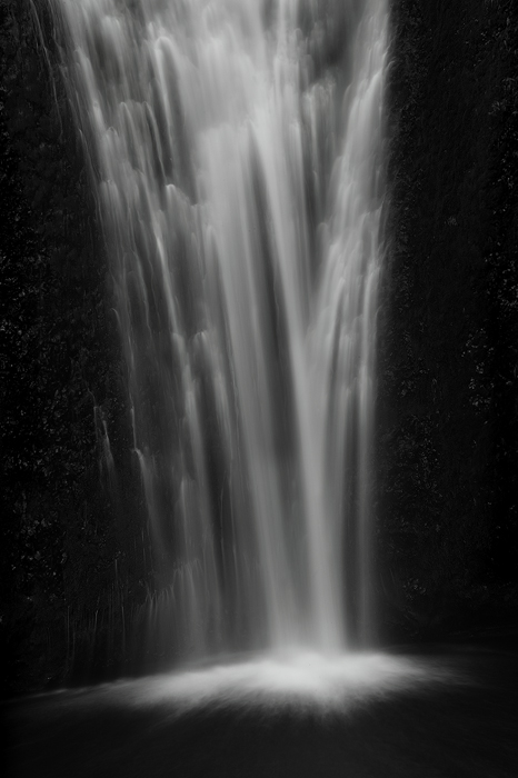A long exposure shows the lower tier of Multnomah Falls flowing down the cliff face and crashing into the creek below.